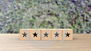 Wooden cube five black star review on blur leaves background. Service rating, satisfaction concept. reviews and comments google