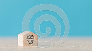 Wooden cube with the icon of idea on a blue blurred background - concept of creativeness, new ideas