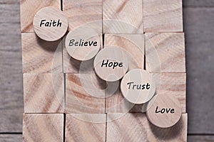 Wooden cube with inspirational text Faith, trust, believe, hope and love. Beautiful wooden table background. Business and Faith