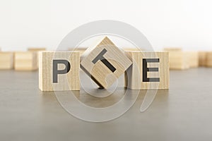 wooden cube with the letter from the PTE word. wooden cubes standing on gray background. PTE - short for Pearson Tests