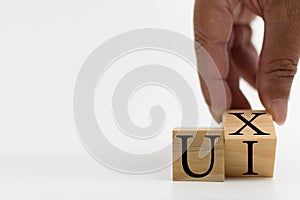 A wooden cube on a white table with text UI, UX. Concept of development and design and development, user interface, user