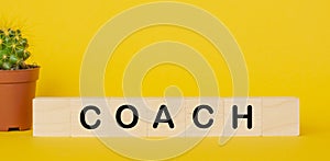 Wooden cube with the word COACH on yellow background. Business concept