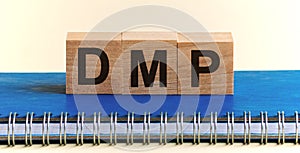 Wooden cubes alphabets building the word DMP - Debt Management Plan acronym. Front view