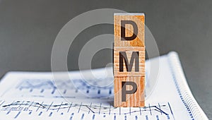 Wooden cubes alphabets building the word DMP - Debt Management Plan acronym. Front view. grey background