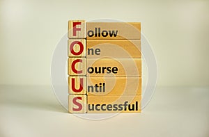 Wooden cubes and blocks with words `FOCUS, follow one course until successful`. Beautiful white background, copy space. Business