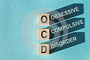 Wooden cubes building word OCD - abbreviation Obsessive Compulsive Disorder on light blue background