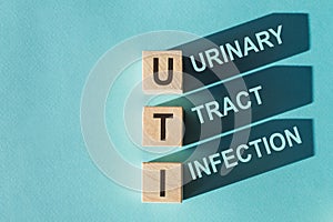 Wooden cubes building word UTI - abbreviation Urinary Tract Infection on light blue background