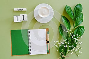 Wooden cubes calendar March 11. Open blank notepad, cup of coffee, bouquet flowers on green background. Concept hello