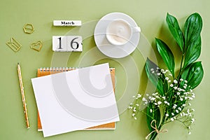 Wooden cubes calendar March 16. Notepad, cup of coffee, bouquet flowers on green background. Concept hello spring Top view Flat