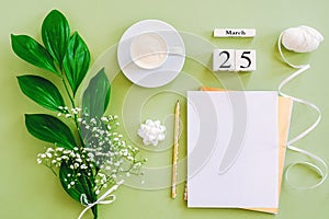 Wooden cubes calendar March 25. Notepad, cup of coffee, bouquet flowers on green background. Concept hello spring Top view Flat