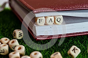 wooden cubes are clamped in a notebook, the word FAQ, the idea of solving questions