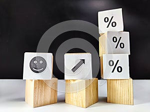 Wooden cubes in a column and a row with white signs with a smiley sign, an arrow, a percentage. The concept of