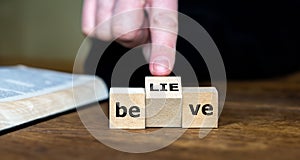 Wooden cubes form the words believe and lie. Symbol for criticizing religions.