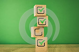 wooden cubes with the image of check marks marks on a green background