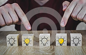 Wooden cubes with the image of a light bulb that symbolizes a new idea, concepts of innovation and solutions, 2 of which poke a