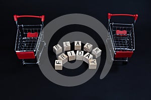 Wooden cubes with the inscription-black Friday on a black background with a supermarket shopping cart