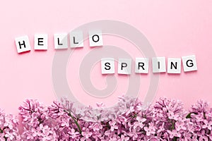 wooden cubes with the inscription hello spring, lilac branches on a pink background, seasonal concept