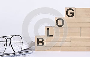 Wooden cubes with letters BLOG on the white table with keyboard and glasses