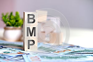 Wooden cubes with the letters BMP arranged in a vertical pyramid on banknotes, business concept photo