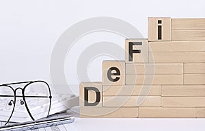 Wooden cubes with letters DEFI on white table with keyboard and glasses