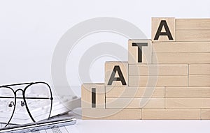 Wooden cubes with letters IATA on the white table with keyboard and glasses