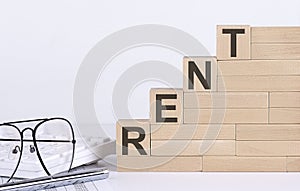 Wooden cubes with letters RENT on the white table with keyboard and glasses