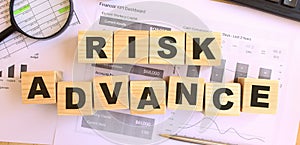 Wooden cubes with letters on the table in the office. Text RISK ADVANCE.