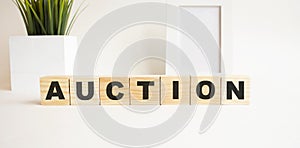 Wooden cubes with letters on a white table. The word is AUCTION. White background