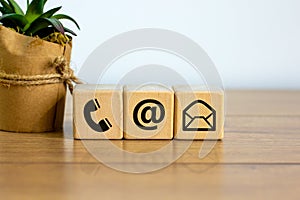 Wooden cubes with mail and phone marks, contact and information icons. Beautiful wooden table, white background. Business concept