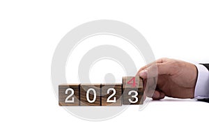 Wooden cubes. The next year is 2024. The year 2023 replaces 2024. The hand flips the dice, changing the years