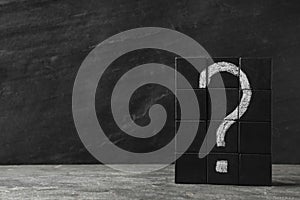 Wooden cubes with question mark on stone table. Space for text