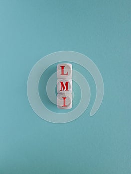 Wooden cubes with the red word LMI. Beautiful blue background, copy space.