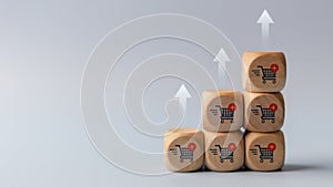 Wooden cubes with shopping cart icons and increasing trend-up graph. Increase higher sale volume and shopping trolley cart for