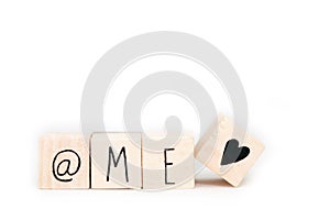 Wooden cubes with a At sign,the word Me and a heart symbol isolated on white background, self love concept