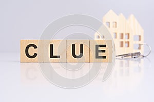 wooden cubes on a table with text CLUE, model house and keys on background. concept of business, financial, investment