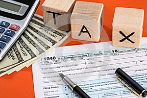 Wooden cubes tax with 1040 foem, pen calculator and dollar