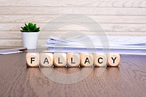 wooden cubes with text FALLACY on brown background