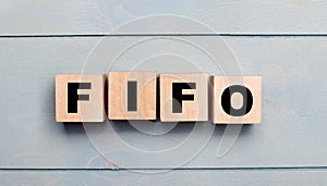 Wooden cubes with the text FIFO First In, First Out on a light blue wooden background