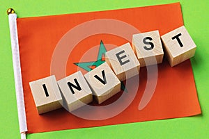 Wooden cubes with text and a flag on a colored background, a concept on the topic of investment in Morocco