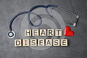 Wooden cubes with text Heart Disease and stethoscope on grey background