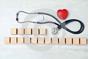 Wooden cubes with text Heart Palpitations and stethoscope on light background