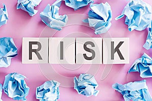 Wooden cubes with the text RISK on a light pink background