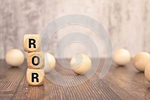 wooden cubes with text ROR - Rate Of Return - on business document