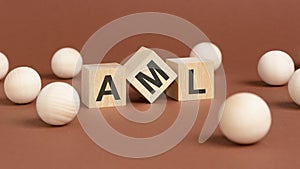 wooden cubes with word AML on brown background. front view
