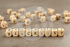 Wooden cubes with word Blacklist on grey table, closeup