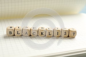 Wooden cubes with word Blacklist on notebook, closeup