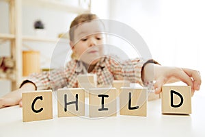 Wooden cubes with word CHILD in hands of little boy