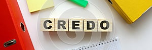 Wooden cubes with word CREDO on the office desk. Folder and other office supplies