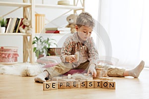 Wooden cubes with word DEPRESSION in hands of little boy