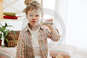 Wooden cubes with word despair in hands of little boy